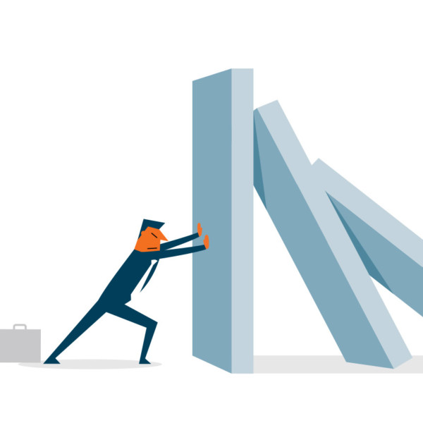Man holding up falling dominos that represent market changes